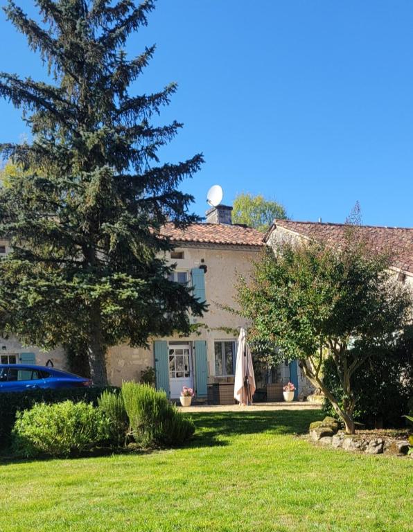 une maison avec un arbre en face d'une cour dans l'établissement Raisin et Toile - French American Retreat, à La Rochebeaucourt-et-Argentine