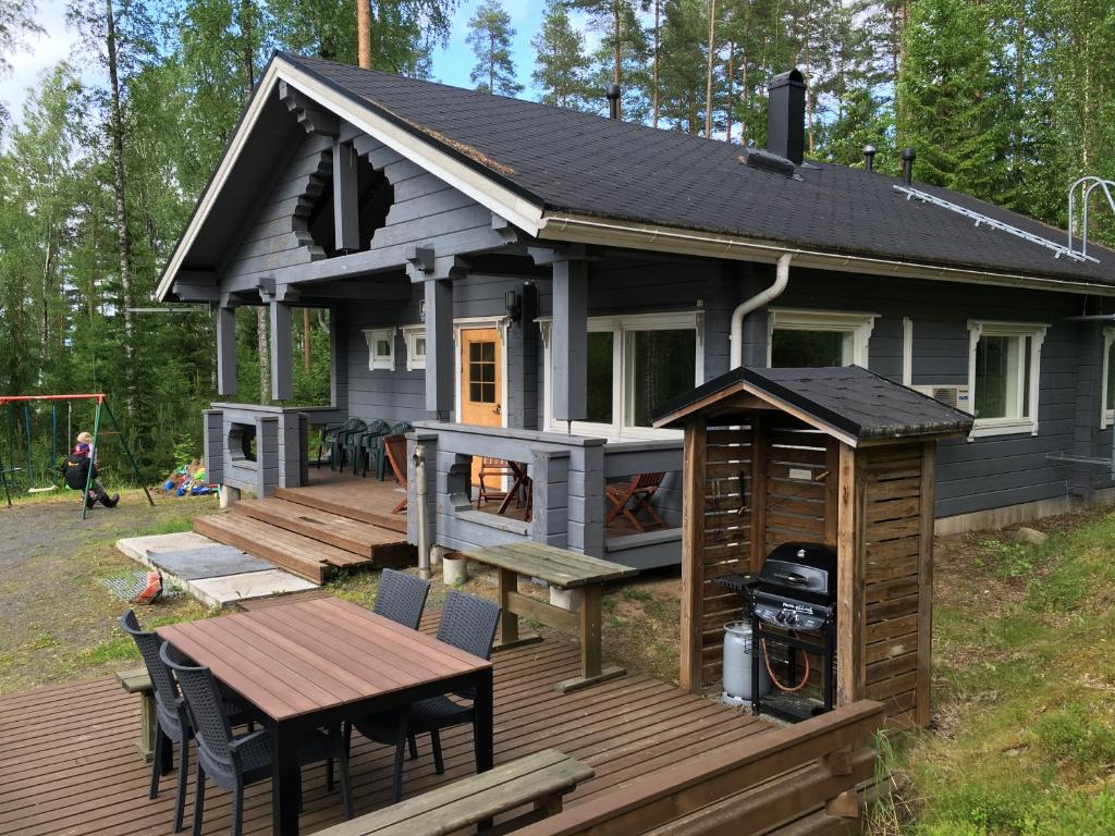 a tiny house with a deck and a table at Kallio-Orava Villa with jacuzzi in Koljonkanta