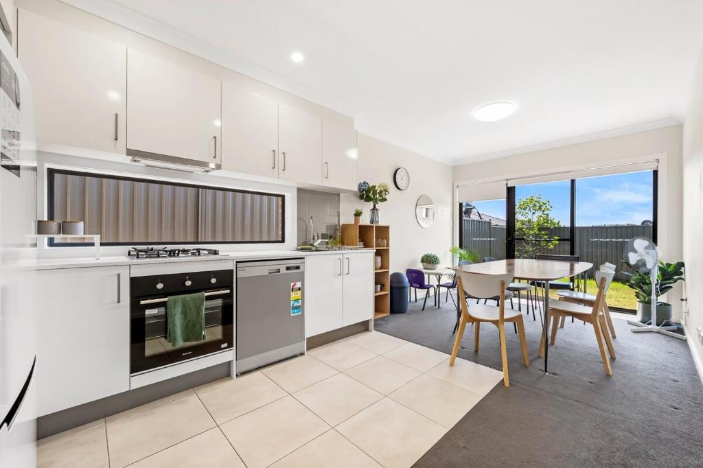 a kitchen and dining room with a table and chairs at KozyGuru | Austral | Charming 4Bedroom Family Home in Austral