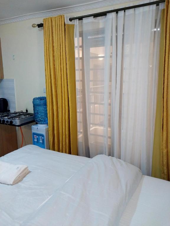 a bedroom with a bed and a window with curtains at Ivy Kendra Kamakis in Ruiru