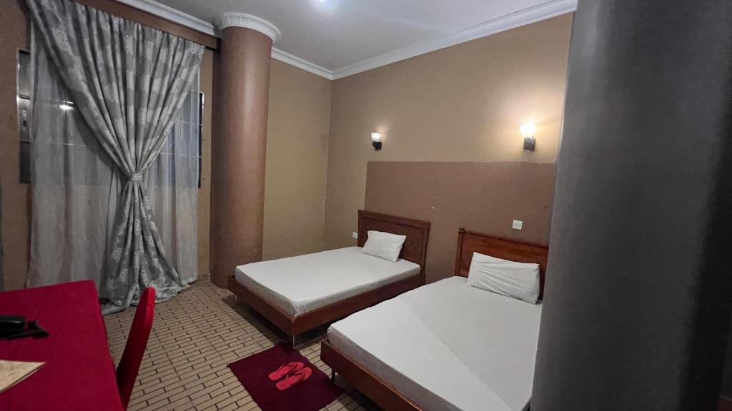 a hotel room with two beds and a window at Lush Garden Hostel in Arusha