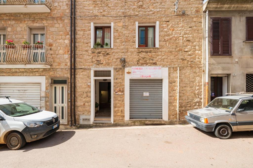 two cars parked in front of a brick building at Su Cilleri e Silbiu in Baunei