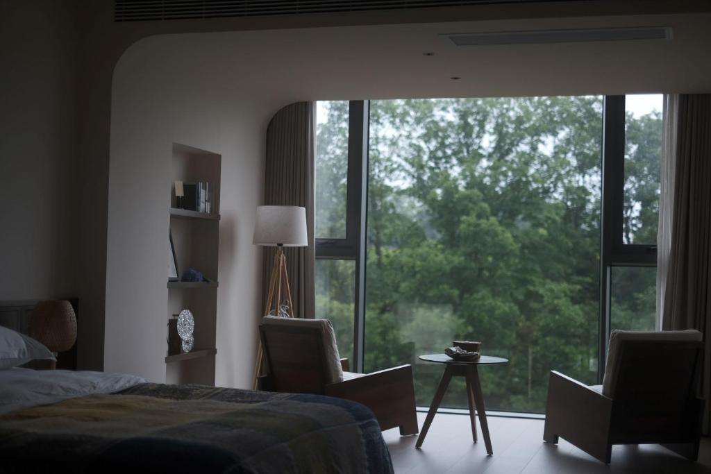 1 dormitorio con 1 cama, 2 sillas y una ventana grande en 张家界大峡谷迴音森林乡村民宿, en Cili