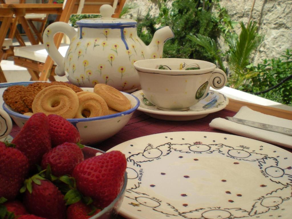 een tafel met borden en bekers en aardbeien erop bij Chicchi Di Melograno in Modica