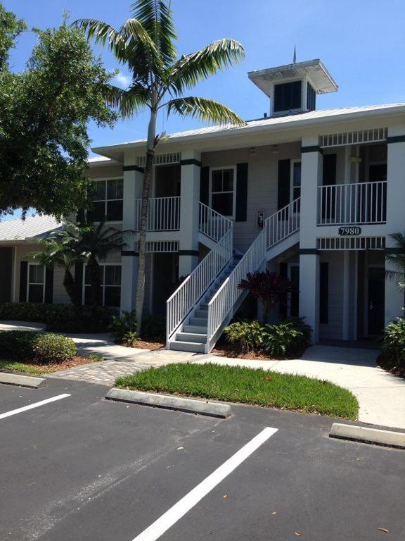 a building with a palm tree in front of a parking lot at Greenlinks Naples Florida Condo in Naples