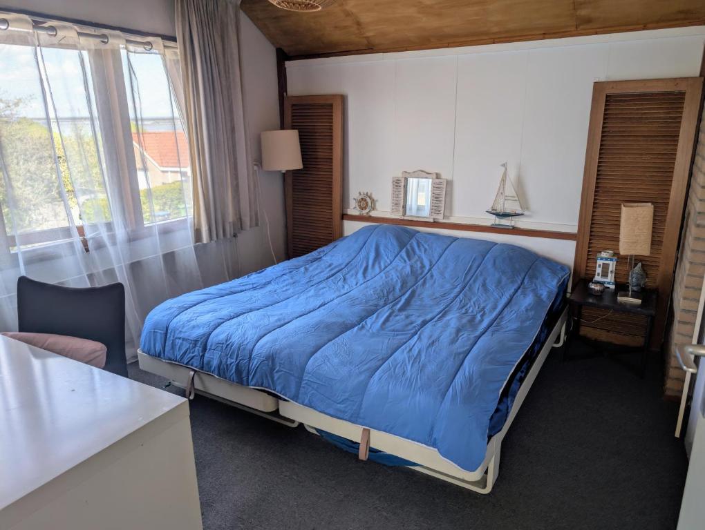 a bedroom with a bed with a blue comforter at 1-2 P Room near Airport AMS freeparking in Roelofarendsveen