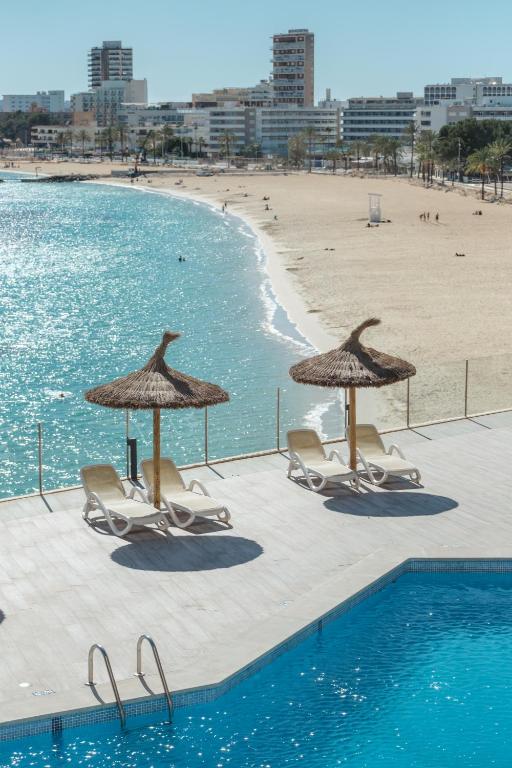 a pool with chairs and umbrellas next to a beach at Bahia Principe Escape Coral Playa Adults Only in Magaluf