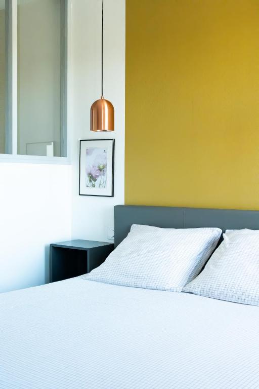 une chambre avec un lit blanc et un mur jaune dans l'établissement Villa Bel-Amy, à Saint-Pair-sur-Mer