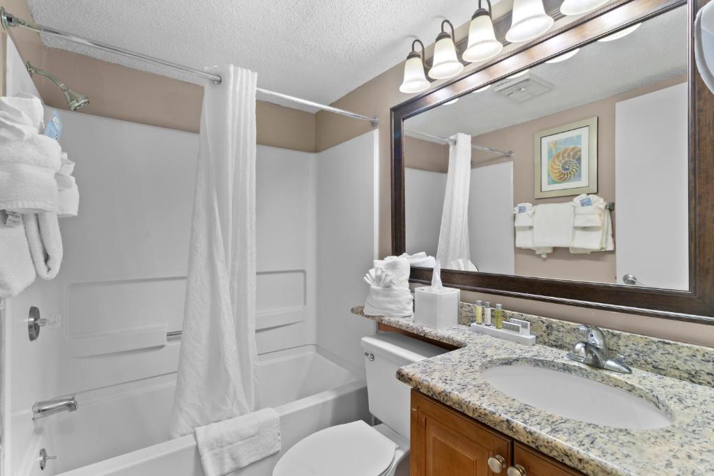 a bathroom with a sink and a toilet and a mirror at The Strand - A Boutique Resort in Myrtle Beach