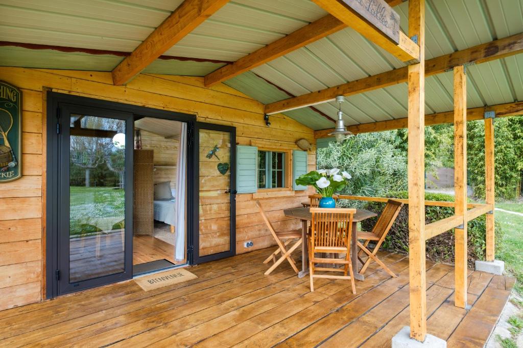 un porche grillagé avec une table et des chaises sur une terrasse en bois dans l'établissement Les Iris le Lac de la Vallée, à La Roquette-sur-Siagne