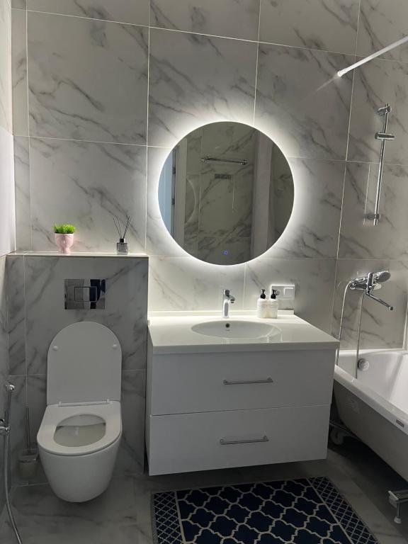 ein Badezimmer mit Toilette, Waschbecken und Spiegel in der Unterkunft Premium Plaza in Aqtau