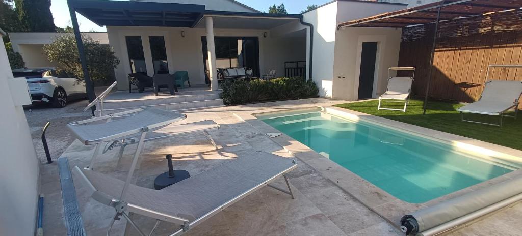 ein Swimmingpool mit zwei Stühlen und einem Tisch neben einem Haus in der Unterkunft L'Orée des Alpilles Proche Centre ville St Rémy de Provence in Saint-Rémy-de-Provence