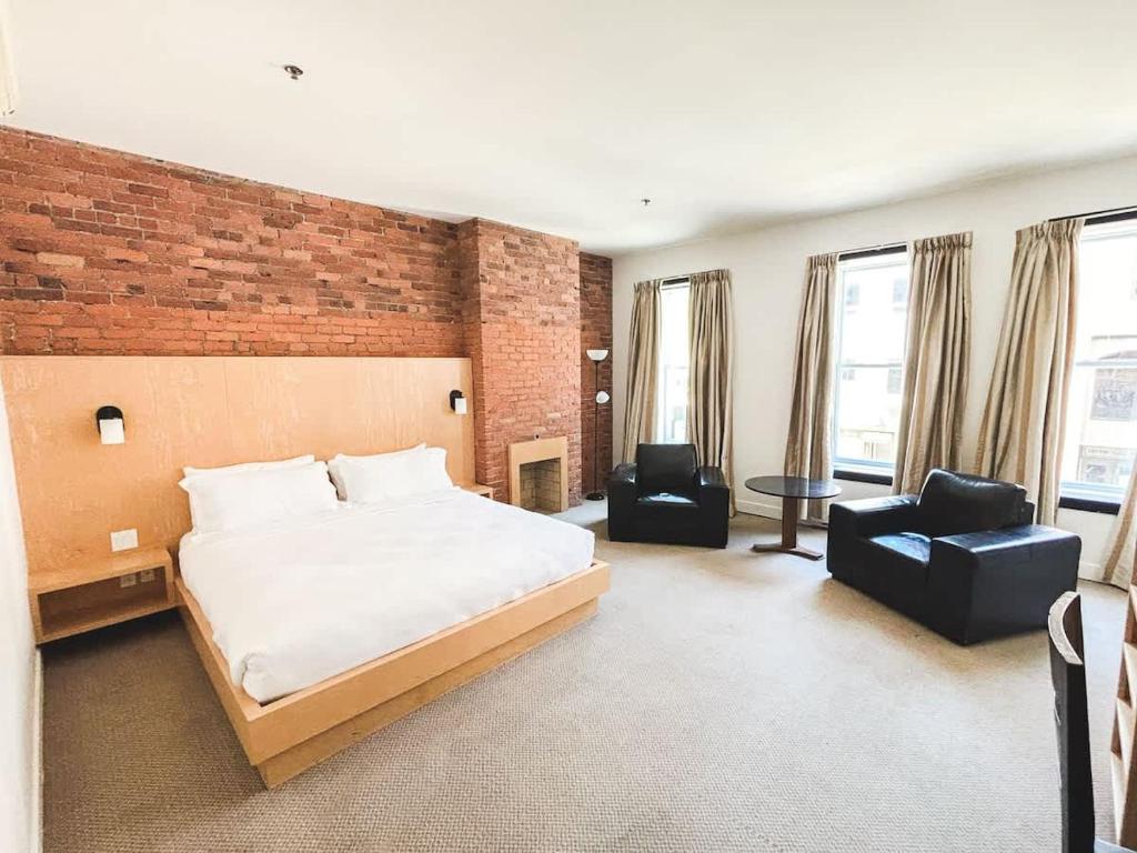 een slaapkamer met een bed en stoelen en een bakstenen muur bij Spacious King Room at The Franklin Hotel Downtown in St. John's