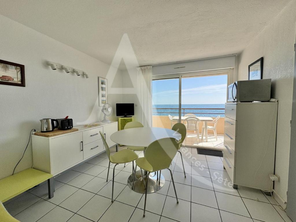 - une cuisine avec une table et des chaises et une vue sur l'océan dans l'établissement APPARTEMENT 1 CHAMBRE BORD DE MER, à Sète