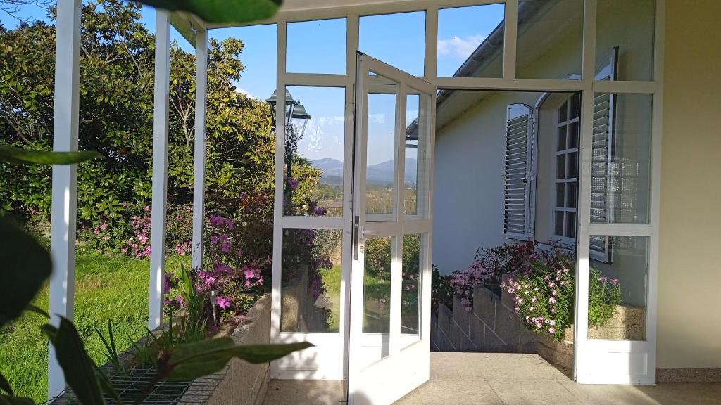 eine offene Glastür zu einem Haus mit Blumen in der Unterkunft La maison d'Abelleira in Puenteareas