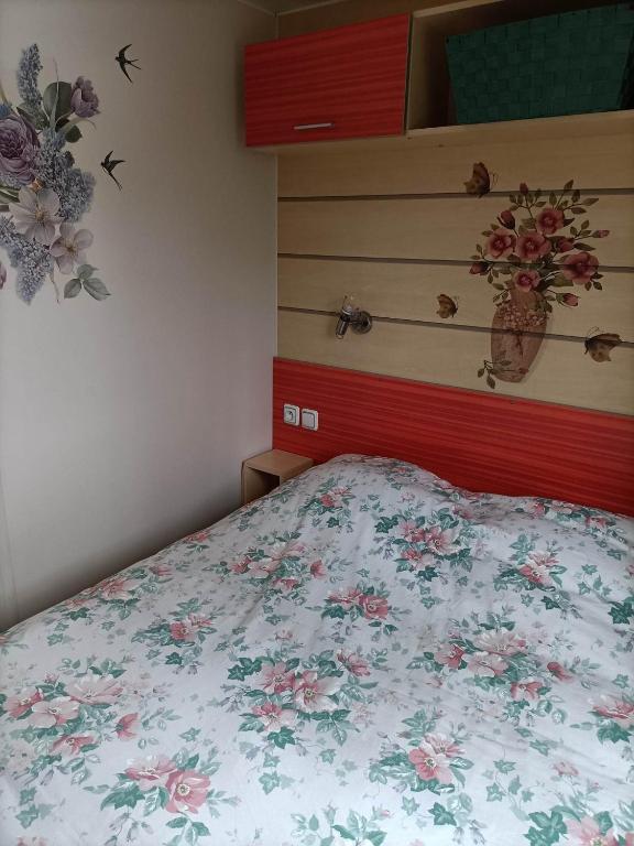 - une chambre avec un lit fleuri dans l'établissement Mobil-home emplacement 3, à Le Chesne