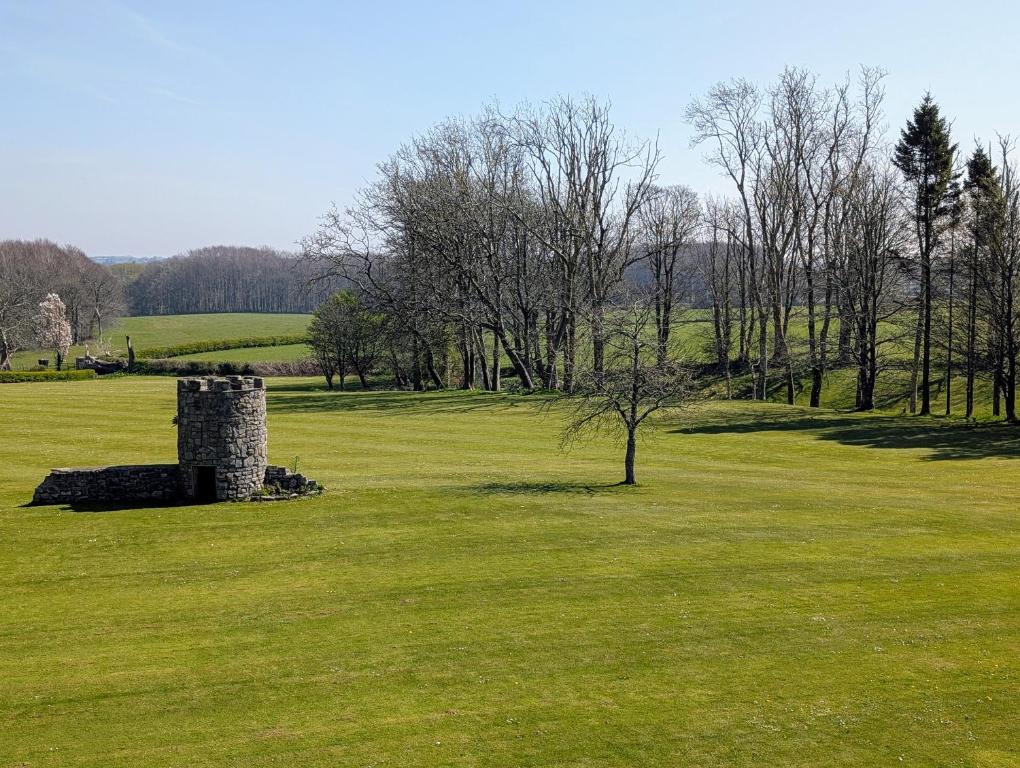a stone tower in a field of green grass at Parc-Le-Breos House in Penclawdd