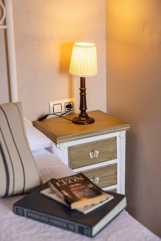 a bed with a table with a lamp and a book at Hotel Puerto Arnela in Camariñas