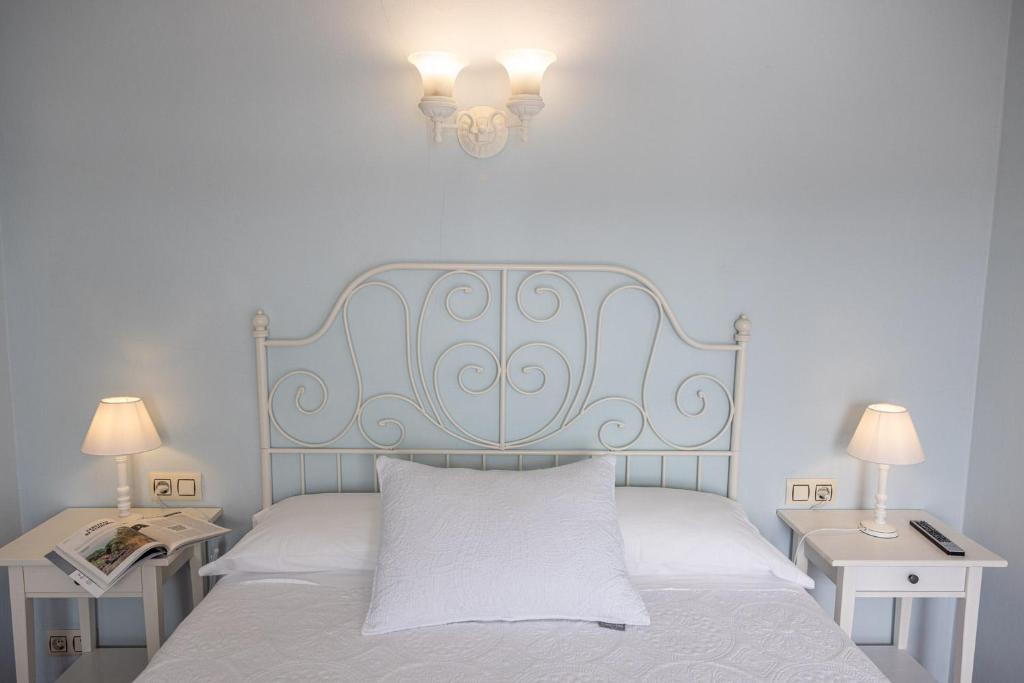 a bedroom with a bed with a blue headboard and two tables at Hotel Puerto Arnela in Camariñas