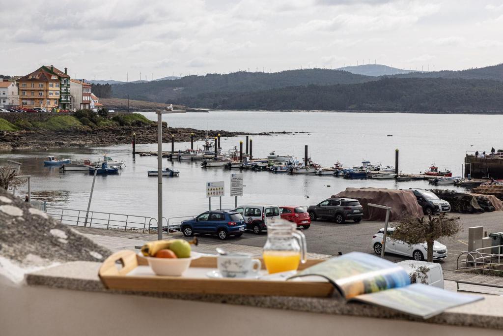 a tray of fruit on a balcony with a view of a harbor at Hotel Puerto Arnela in Camariñas