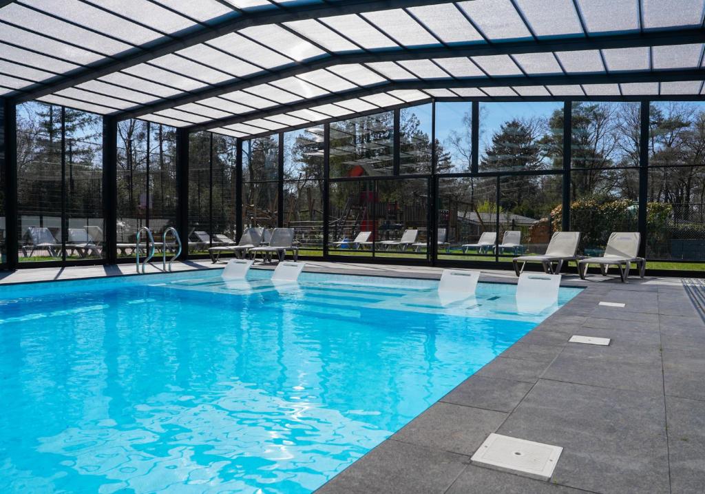une grande piscine avec un toit rétractable dans l'établissement Vakantiepark De Rimboe & De Woeste Hoogte, à Hoenderloo
