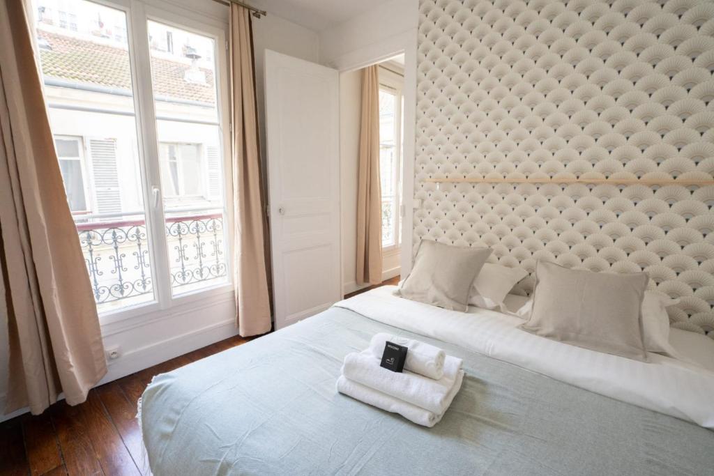 une chambre avec un grand lit avec des serviettes dessus dans l'établissement Appartement voltaire refait a neuf - 2P paris 11, à Paris