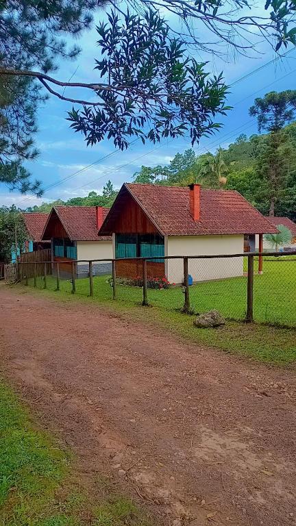 a house with a fence next to a dirt road at Palmeira Azul in Visconde De Maua