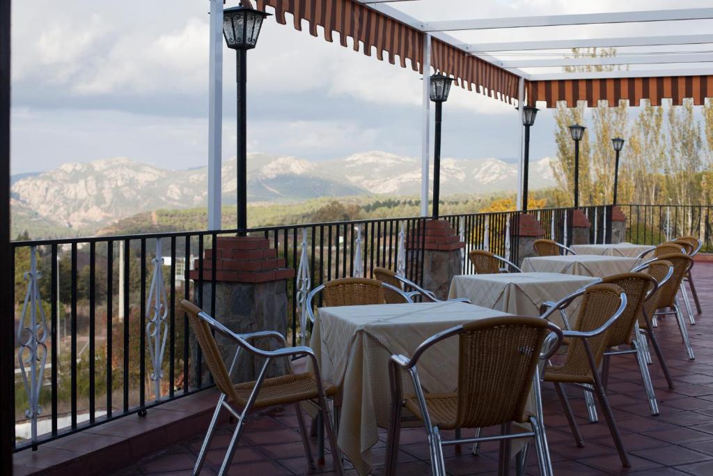 una fila de mesas y sillas en un balcón con montañas en El Mesón de Despeñaperros en Santa Elena