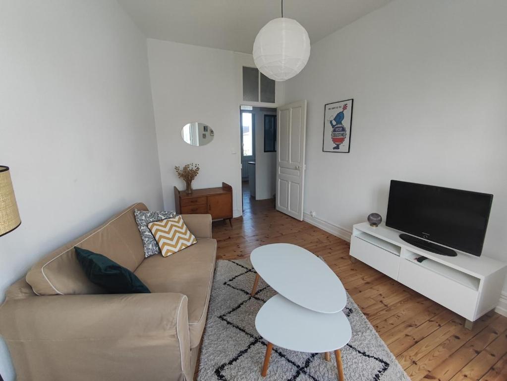 un salon avec un canapé et une télévision dans l'établissement Appartement lumineux refait à neuf, cœur de ville, à Vichy