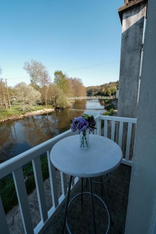 une table sur un balcon avec un vase de fleurs dans l'établissement Appartement Le Balcon de L'Oust, à Malestroit