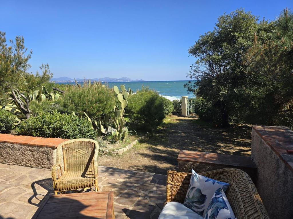 un patio avec une table et des chaises et l'océan dans l'établissement Villa les ifs pieds dans leau, aux Issambres