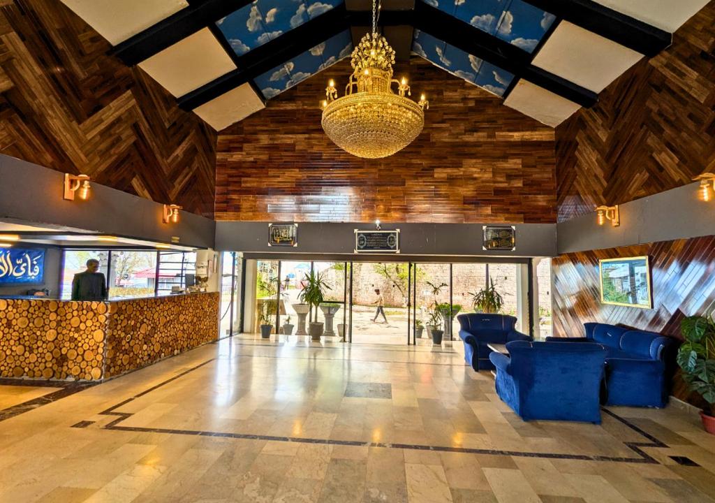 a lobby with blue chairs and a chandelier at Grand Heights Hotel in Murree