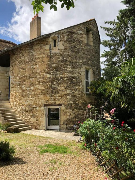 an old stone building with a door and some flowers at La tour du logis in Chéneché