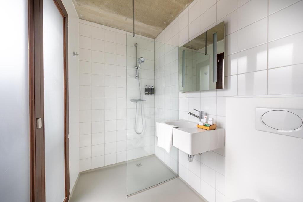 uma casa de banho branca com um lavatório e um chuveiro em BANKS Antwerp em Antuérpia
