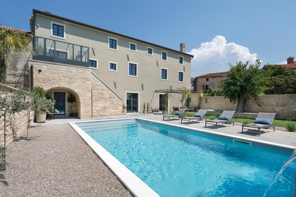 a house with a swimming pool in front of a building at Luxury Villa Covri in Brtonigla