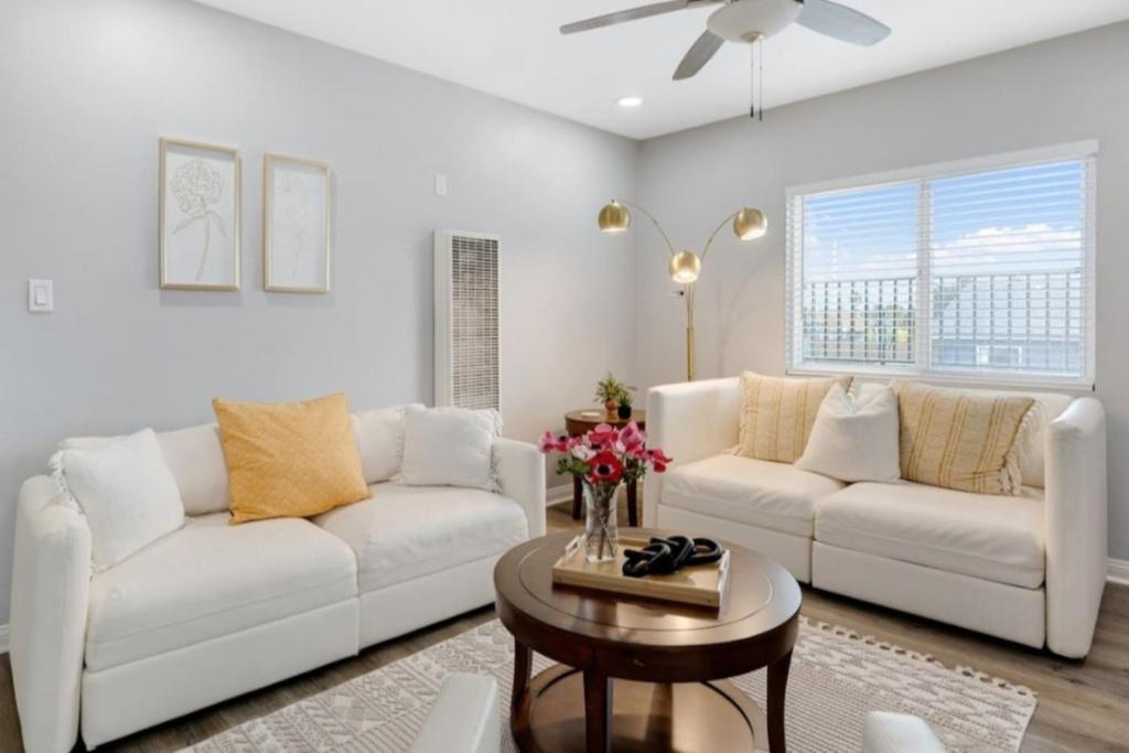 Una sala de estar con dos sofás blancos y una mesa. en Leyla Pool Spa Min to Downtown Freeways Beaches, en San Diego