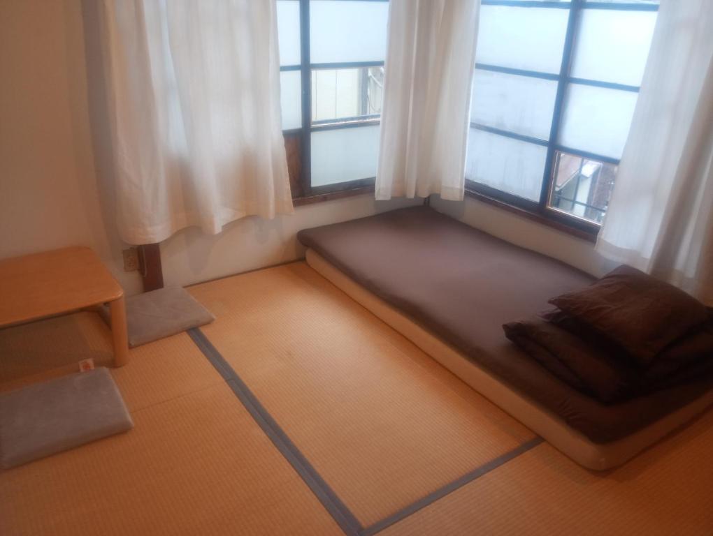 un letto in una stanza con due finestre di Edo Tokyo Sharehouse Long Stay Only, One month plus a Tokyo