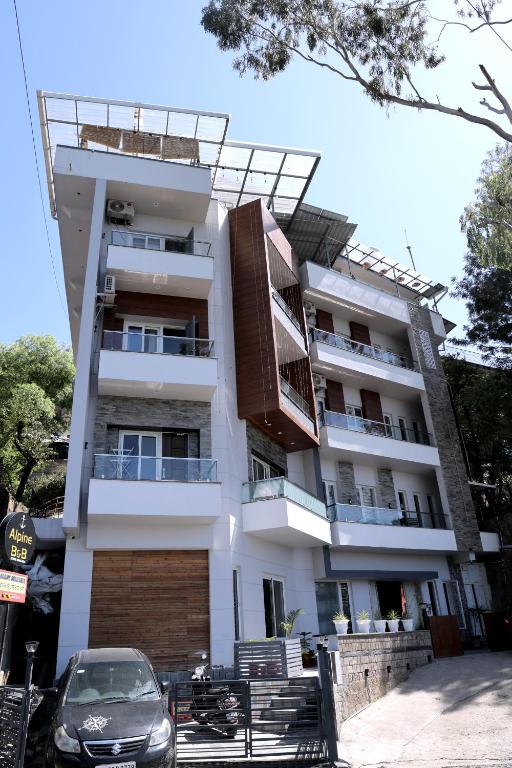 a building with a car parked in front of it at ALPINE BNB Dharmshala Homestay in Dharamshala