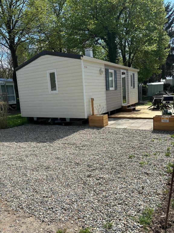 Une petite maison blanche assise sur un terrain de gravier dans l'établissement mobil-home camping du ried, à Boofzheim