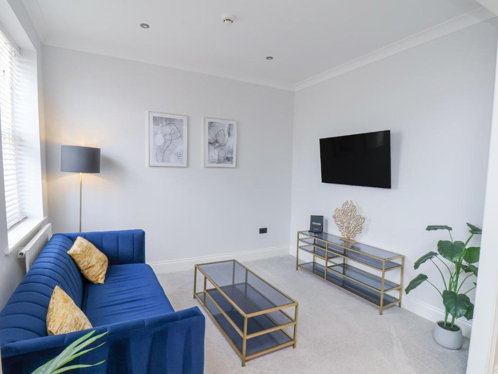 Una sala de estar con un sofá azul y un televisor. en The Salisbury - 1 Bedroom Deluxe Apartment, en Scarborough