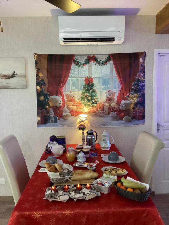 una mesa con un mantel rojo con comida. en Chambre d'hôtes la Maximinoise à 5mn de Chantilly et à proximité de Senlis et autoroute A1,Parc Astérix, Pierrefonds, Compiegne, Aéroport Roissy Charles de Gaulle, en Saint-Maximin