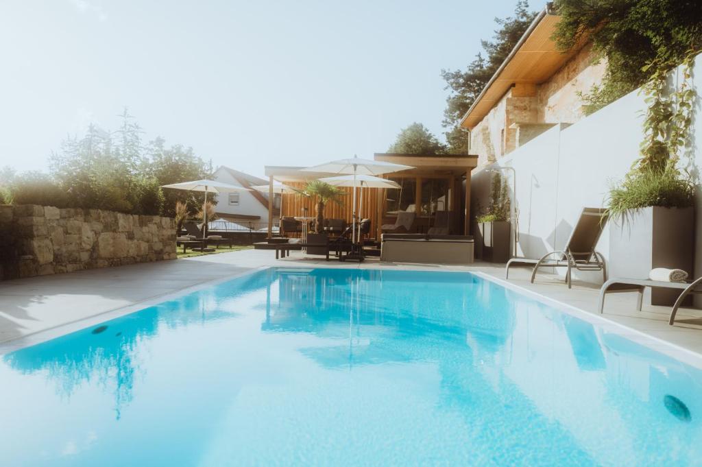 a large blue swimming pool with chairs and umbrellas at Landgasthof & Hotel zur Rose Berg in Ehingen