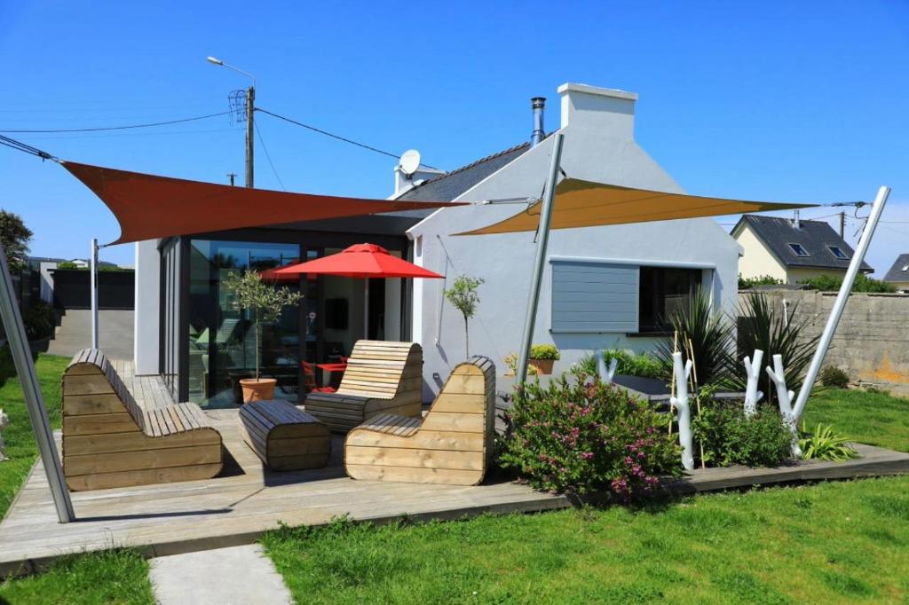 une terrasse avec des chaises et un parasol en face d'une maison dans l'établissement charmante maison avec jardin clos sur les dunes de Sainte Marguerite avec SPA en option, à Landéda