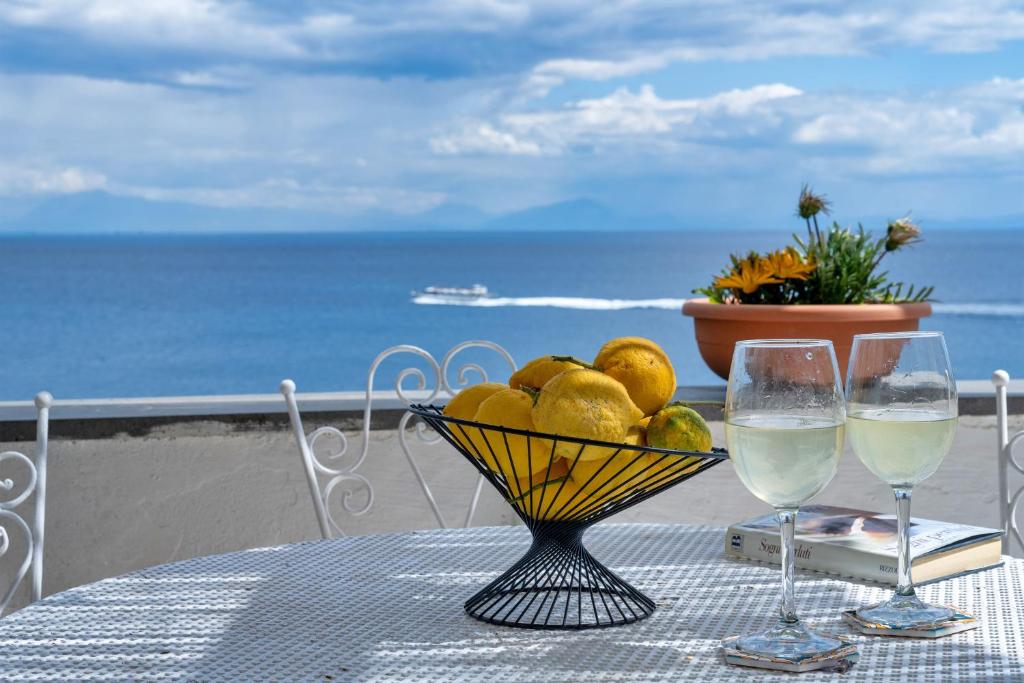 a table with a bowl of fruit and two glasses of wine at Villa Gianna "Nonna Gianna's Home Amalfi Coast" in Conca dei Marini