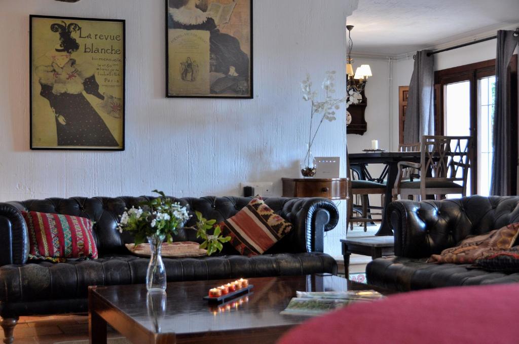 a living room with black leather couches and a table at Casa Rural Finca Buenavista in Valdeganga de Cuenca