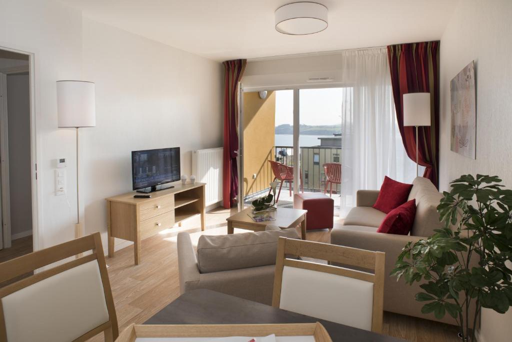 a living room with a couch and a tv at Domitys Les Gréements d'Or in Douarnenez