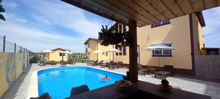 ein Swimmingpool mit Stühlen und Sonnenschirmen neben einem Gebäude in der Unterkunft La Toscana Costinești in Schitul