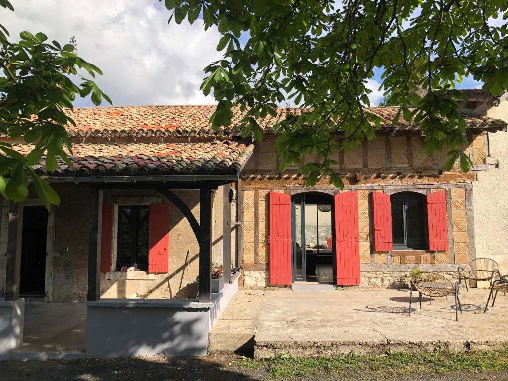 a building with red doors and a table and chairs at Le Marronnier in Villeréal