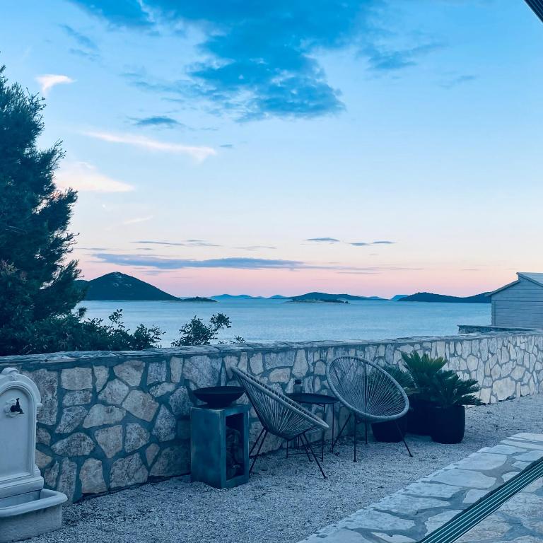 a stone wall with two chairs and a table at Adriatic Dream - Mobile Home - Oaza Mira in Drage