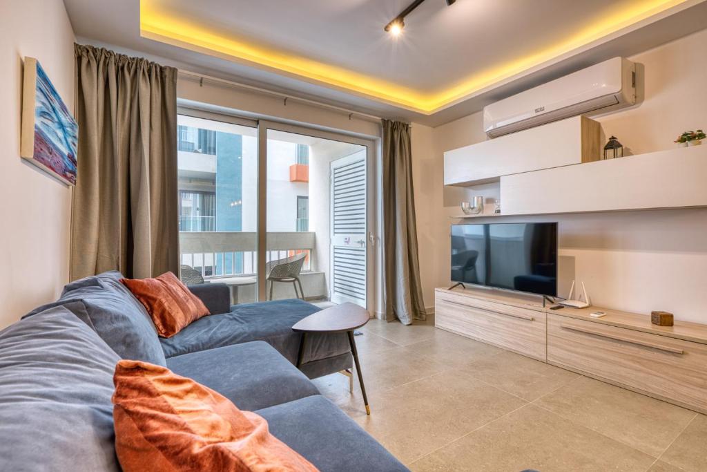 Una sala de estar con un sofá azul y un televisor. en Modern 2-Bedroom Apartment Near the Sea, en St Paul's Bay